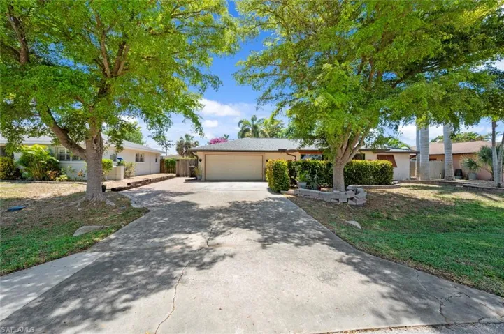 Ranch-style house with driveway, fence, a garage, and stucco siding
