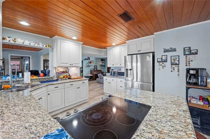 Kitchen with visible vents, white cabinets, a sink, wood ceiling, and stainless steel appliances