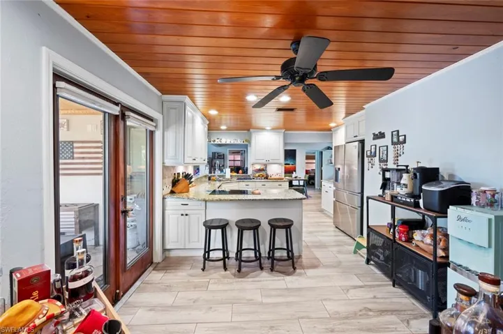 Kitchen featuring stainless steel refrigerator with ice dispenser, ornamental molding, a ceiling fan, a peninsula, and wood ceiling