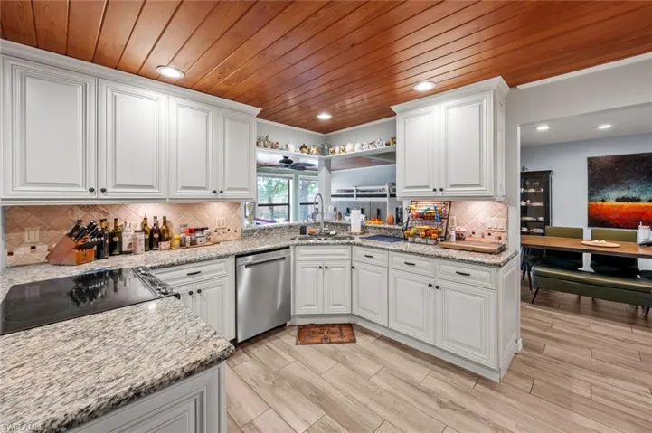 Kitchen featuring a sink, cooktop, stainless steel dishwasher, and wooden ceiling