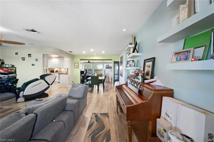 Living room featuring visible vents, ceiling fan, arched walkways, and light wood-style floors
