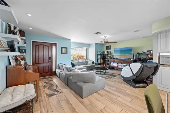 Living area featuring light wood-style flooring, ceiling fan, visible vents, and recessed lighting