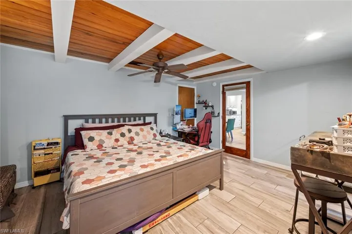 Bedroom with a ceiling fan, wood ceiling, wood finished floors, baseboards, and beam ceiling
