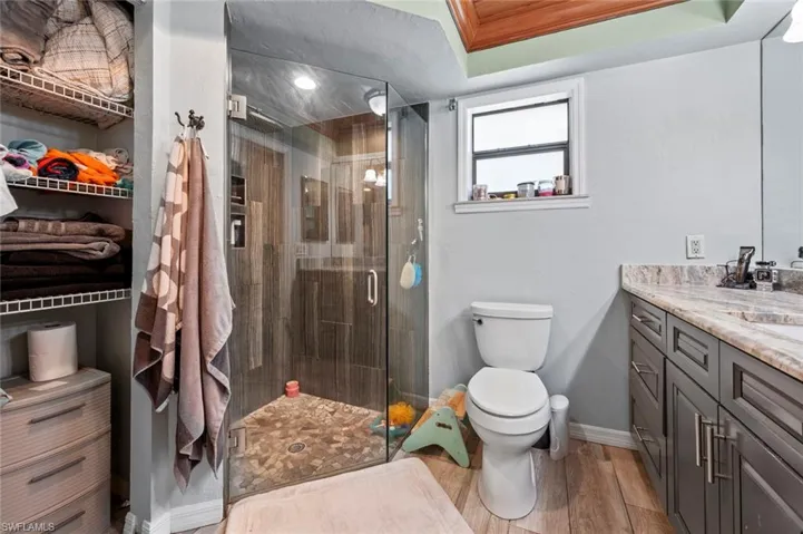 Full bathroom with vanity, baseboards, toilet, a shower stall, and wood finished floors