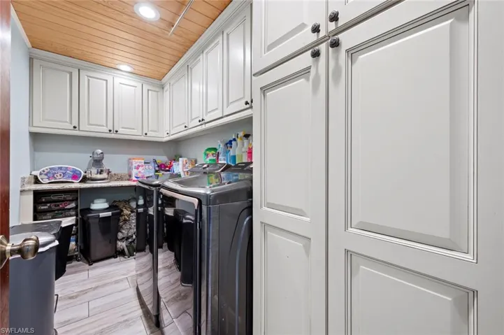 Laundry room with recessed lighting, washing machine and dryer, light wood-style flooring, cabinet space, and wooden ceiling