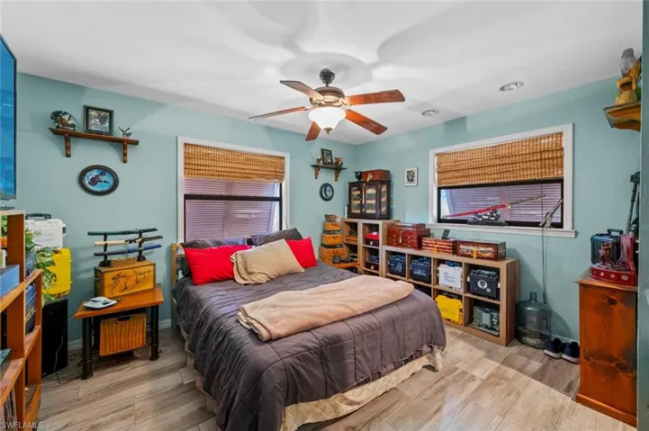 Bedroom with multiple windows, a ceiling fan, and wood finished floors