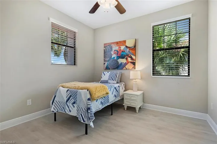Bedroom with light LVP  floors and ceiling fan