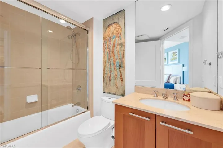 Ensuite bathroom featuring bath / shower combo with glass door and vanity