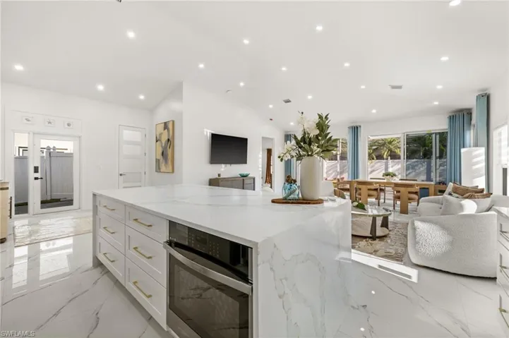 Kitchen featuring open floor plan, light stone countertops, stainless steel oven, a center island, and recessed lighting