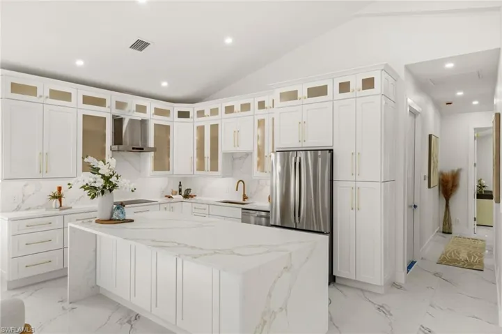 Kitchen with recessed lighting, light stone countertops, lofted ceiling, exhaust hood, and a center island