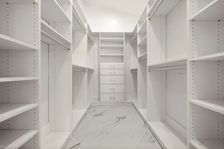 Walk in closet featuring light marble finish floors