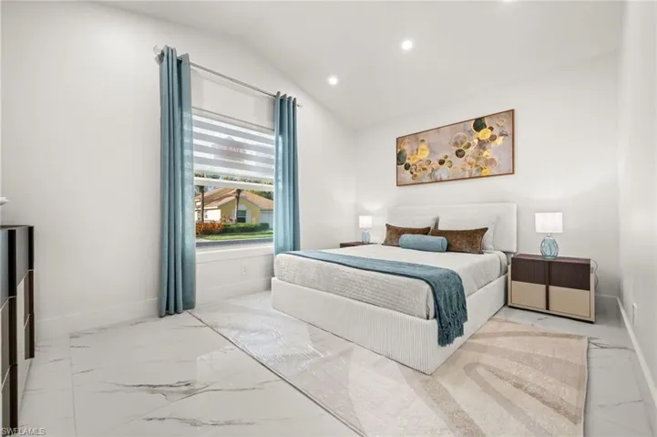 Bedroom with lofted ceiling, recessed lighting, and light marble finish flooring