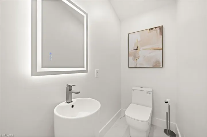 Half bathroom with baseboards and marble look tile flooring