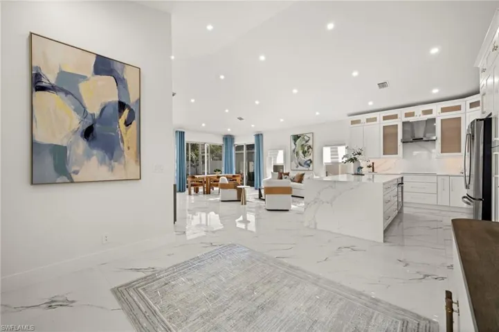 Kitchen featuring white cabinetry, light stone counters, glass fronted cabinets, open floor plan, and freestanding refrigerator