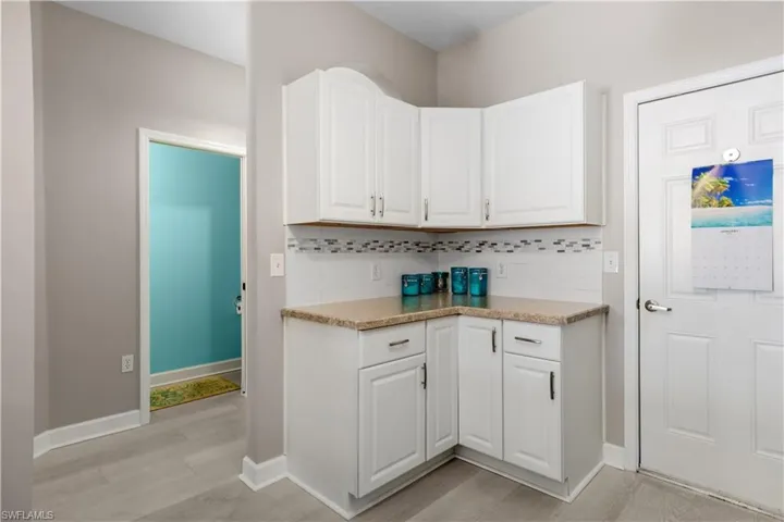 Kitchen featuring tasteful backsplash, additional corner cabinets and half bath off the foyer