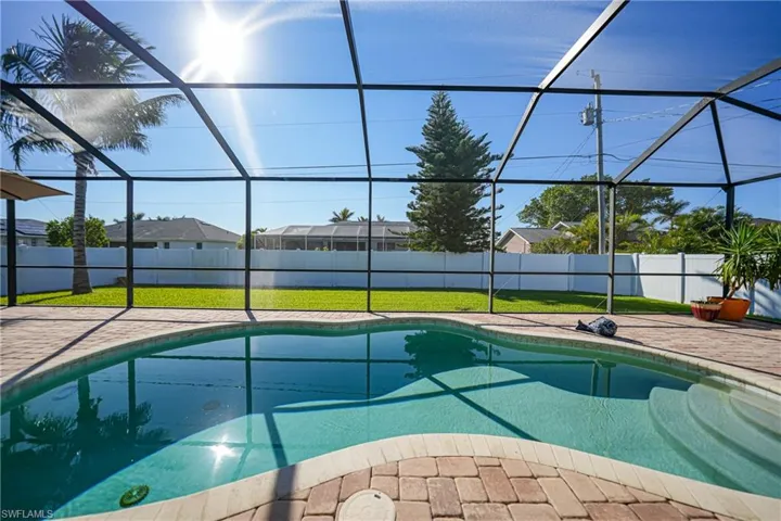 View of swimming pool featuring a lawn, glass enclosure, and a patio