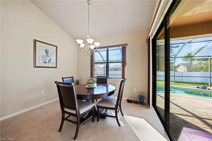 Tiled dining space with lofted ceiling and a notable chandelier