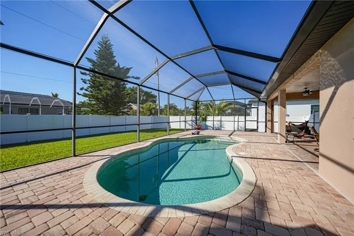 View of swimming pool featuring a lawn, glass enclosure, ceiling fan, and a patio area