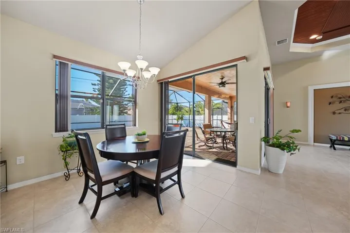 Dining area featuring lofted ceiling, light tile patterned floors, and ceiling fan with notable chandelier
