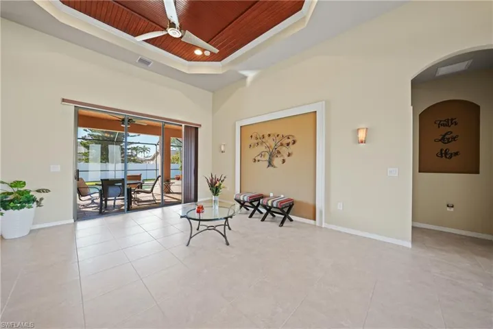 Sitting room with ceiling fan, a raised ceiling, wooden ceiling, and light tile patterned floors