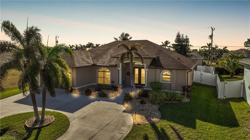 View of front of home featuring roof with shingles, stucco siding, concrete driveway, a lawn, and a gate
