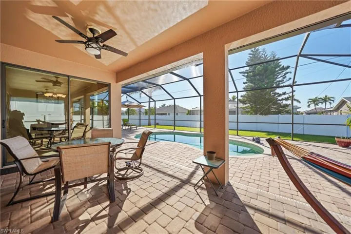 View of patio with glass enclosure, ceiling fan, and a fenced in pool