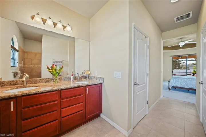 Bathroom with tile patterned floors, ceiling fan, a shower, and vanity