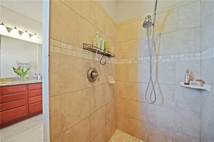 Bathroom with tile patterned flooring, vanity, and a tile shower