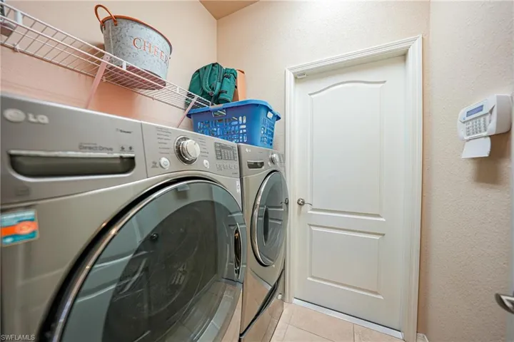 Laundry room featuring light tile patterned floors and washing machine and clothes dryer