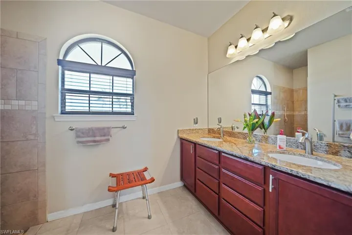 Bathroom with tile patterned flooring, a tile shower, and vanity