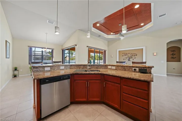 Kitchen featuring sink, dishwasher, wooden ceiling, decorative light fixtures, and a center island with sink