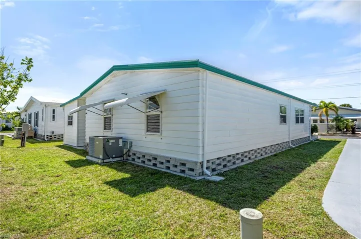View of side of property with central AC unit and a yard