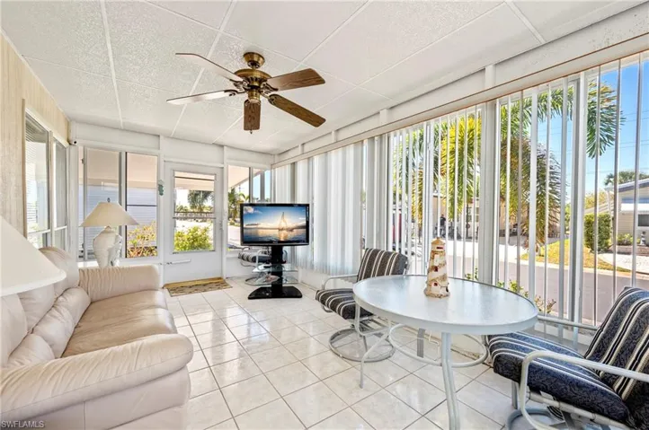 Sunroom with tile patterned flooring, plenty of natural light, and a drop ceiling