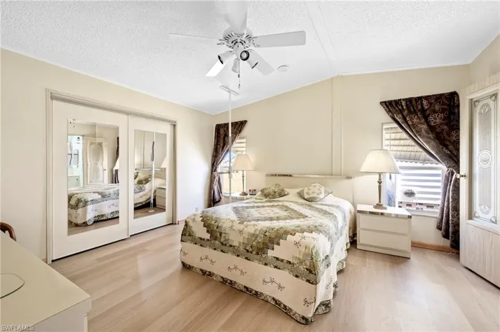 Bedroom with light wood-type flooring, lofted ceiling, and multiple windows