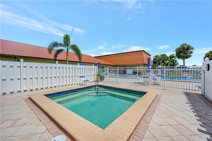 Community pool featuring a patio area, a hot tub, and fence