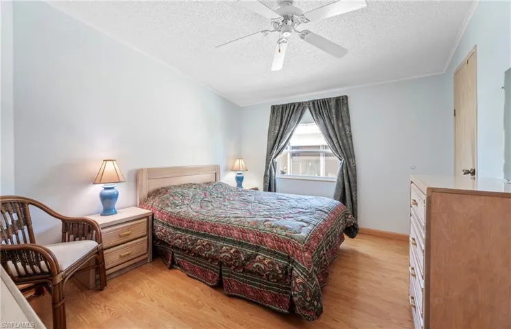 Bedroom featuring a textured ceiling, ceiling fan, light wood finished floors, and ornamental molding