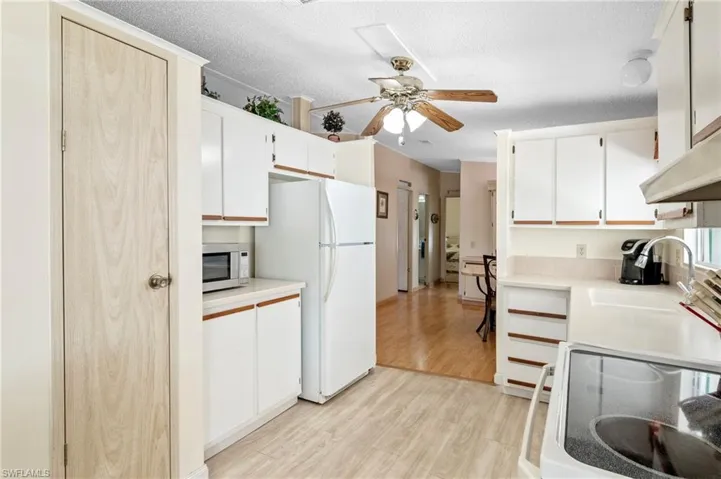 Kitchen with light countertops, freestanding refrigerator, light wood-style floors, a ceiling fan, and range