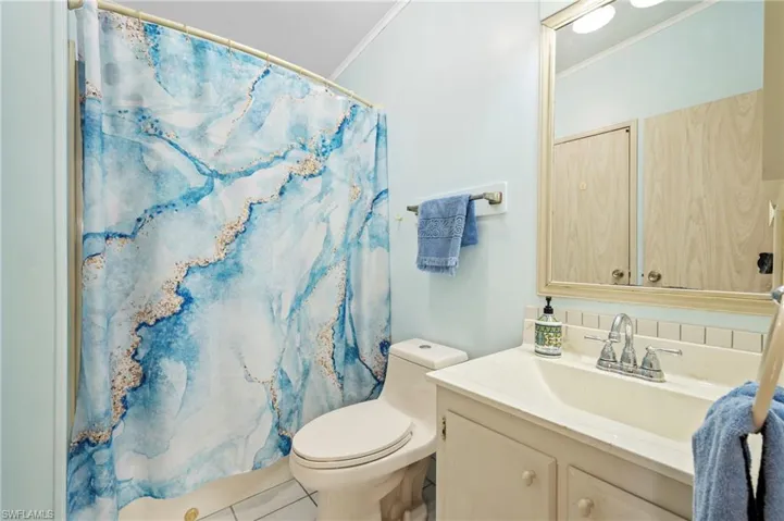 Full bathroom featuring curtained shower, vanity, toilet, and crown molding