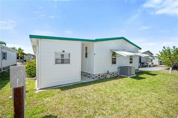 Back of property with central AC unit and a lawn