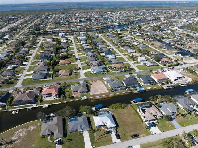 Aerial view of property and surrounding area featuring nearby suburban area and a nearby body of water