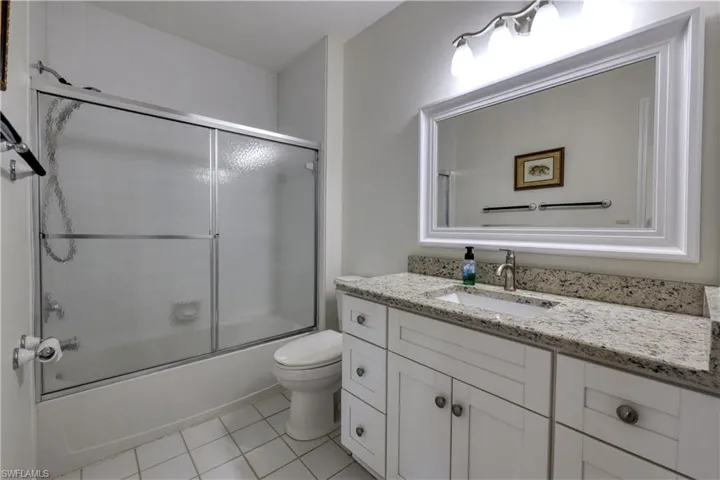 Full bath featuring shower / bath combination with glass door, vanity, and light tile patterned floors