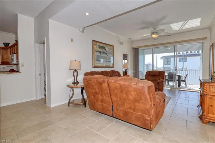 Living area featuring crown molding, ceiling fan, and light tile patterned floors