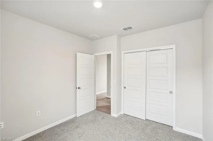 Unfurnished bedroom with light carpet and a closet