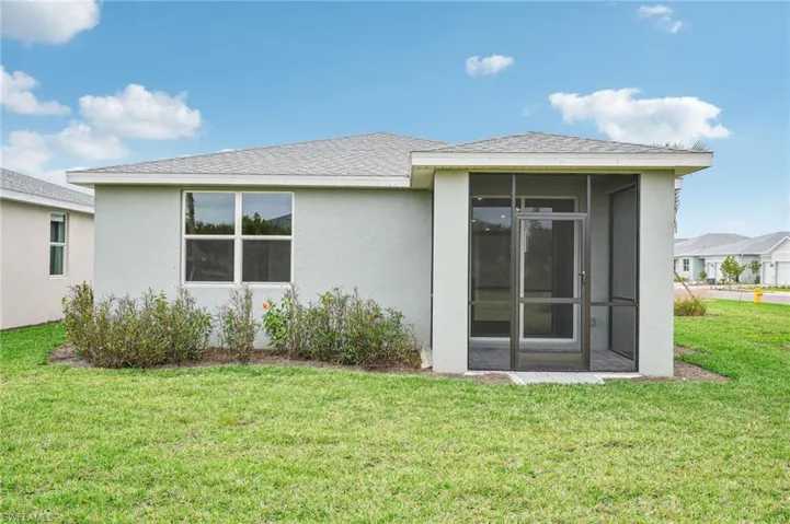Back of property with a lawn and a sunroom