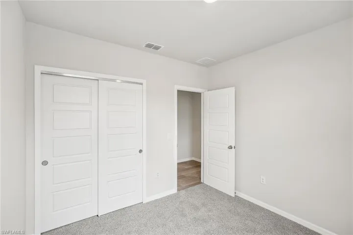 Unfurnished bedroom featuring a closet and light colored carpet