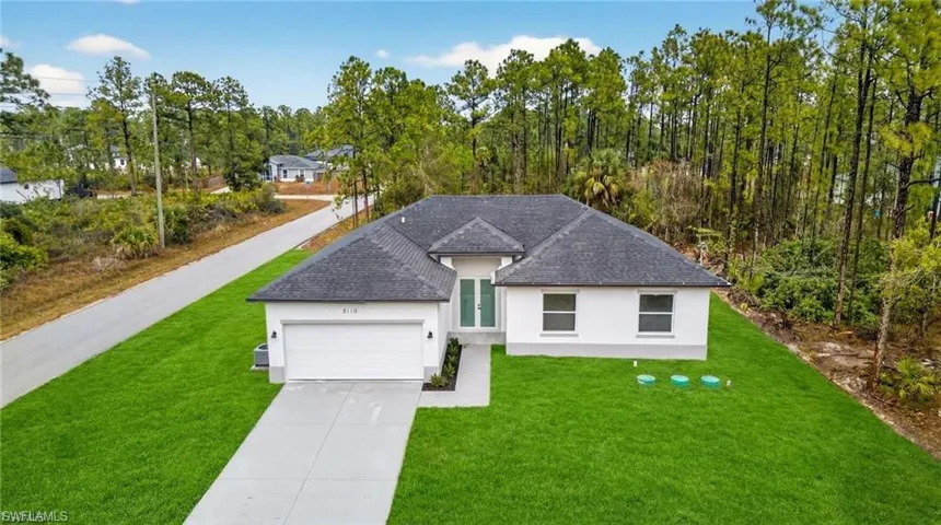 View of front of home featuring a front yard, stucco siding, roof with shingles, concrete driveway, and a garage