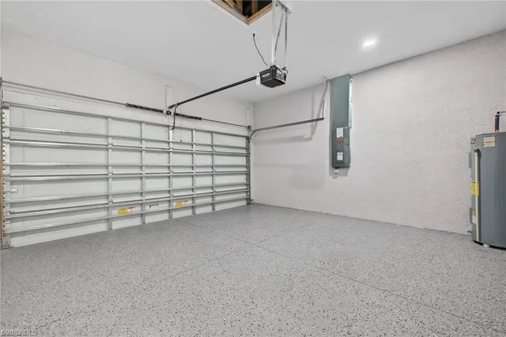 Garage featuring electric panel, water heater, and a garage door opener