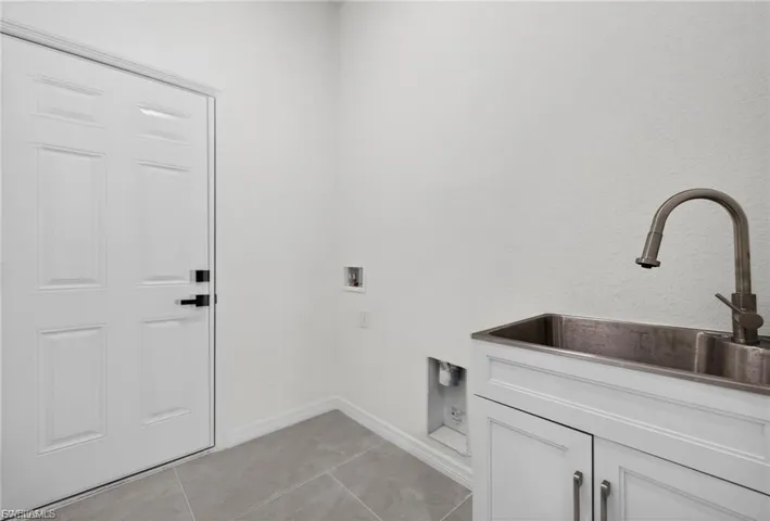 Laundry area with washer hookup and light tile patterned flooring
