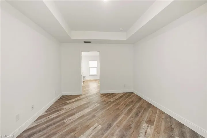 Master bedroom with tray ceiling. There is a pocket door as you pass through toward the bathroom and closets.