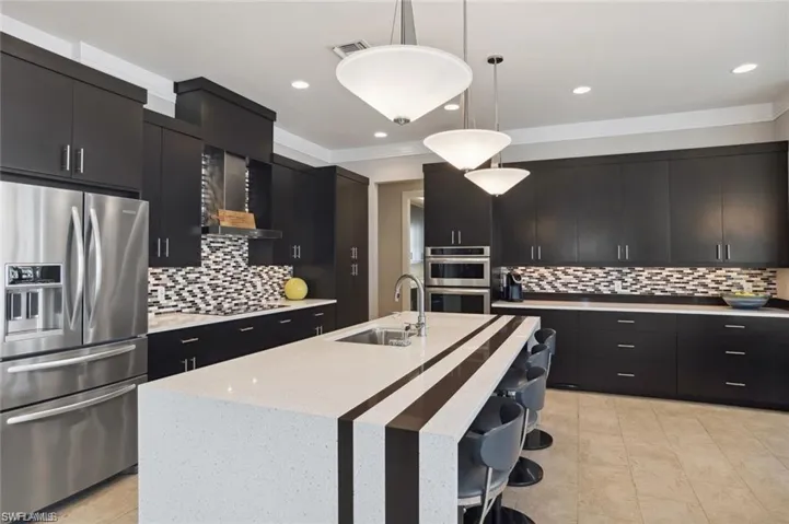 Kitchen with stainless steel appliances, dark cabinetry, a sink, and visible vents